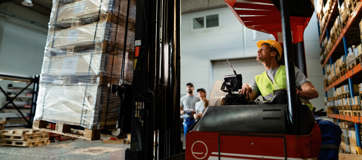 forklift-operator-loading-cargo-while-working-warehouse-his-colleagues-are-background 1